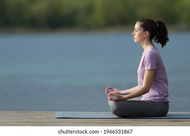 Profile Of A Yogi Practicing Yoga In A Pier Beside A Lake