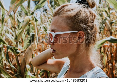 Profile of young and beautiful blonde woman in nature with white sunglasses