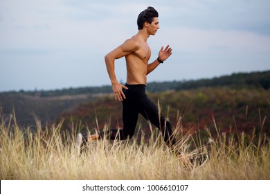 Profile of young brunette fit, shirtless torso, six pack abs athletic, runner outside. Concept of healthy active lifestyle. Isolated on field, autumn, nature landscape background. Horizontal view. 