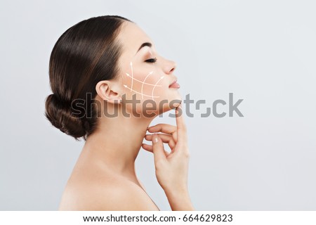 Profile of young female with clean fresh skin, antiaging concept. Girl touching face with closed eyes, lifting arrows showing facial anti-aging treatment on skin ストックフォト © 