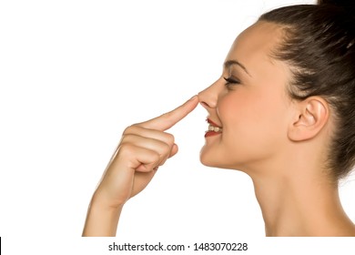 profile of young happy woman touches her nose with her finger on a white background