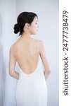 Profile of a young Japanese woman in a beautiful white dress with an open back. Close-up of the back. Image of esthetics, hair removal and slimming.