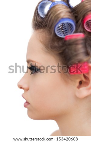 Profile of young model with hair curlers on white background
