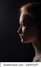 profile of young pensive woman with red hairs on black background