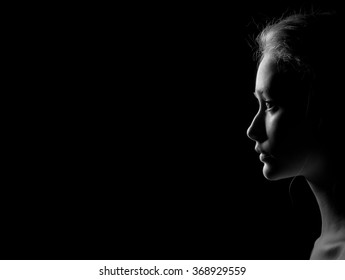 profile of young pensive woman with red hairs on black background with copyspace, monochrome