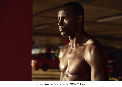 Profile Of Young Serious Athletic Black Man Looking Away At Sunny Day. Concept Of Healthy Lifestyle. Handsome Muscular Bald Guy With Naked Torso On Blur Background Of Parking Lot