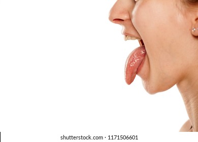 Profile of young woman with her tongue out on white background