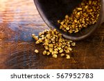 Profit, trade and exchange. Gold nuggets spilling out from a grungy old metal container, placed on a old wooden table.Shallow depth of field.