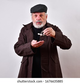 Profiteer Offering To Sell Scarce Hand Sanitizer On Thre Black Market.
Old Man Dressing In A Shabby Trenchcoat Is Selling Hand Sanitizer On The Black Market.