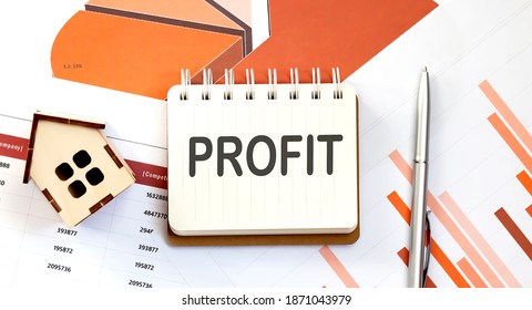 PROFT text on notepad with paper sheet with pen and wooden house