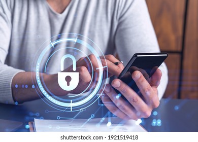A programmer is browsing the Internet in smart phone to protect a cyber security from hacker attacks and save clients confidential data. Padlock Hologram icons over the typing hands.