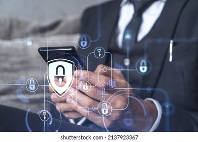A programmer is browsing the Internet in smart phone to protect a cyber security from hacker attacks and save clients confidential data. Padlock Hologram icons over the typing hands. Formal wear. - Shutterstock ID 2137923367