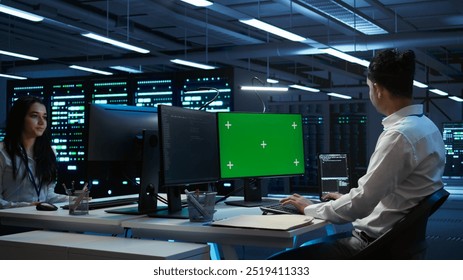 Programmer in data center managing and maintaining databases using mockup PC, ensuring data integrity and security. Expert updating server room systems using green screen computer, camera B