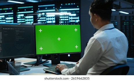 Programmer in data center managing and maintaining databases using mockup PC, ensuring data integrity and security. Expert updating server room systems using green screen computer, camera A