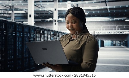 Programmer in data center uses laptop to upgrade systems for increased stability, while IT professional in server farm configures infrastructure with notebook for optimum performance