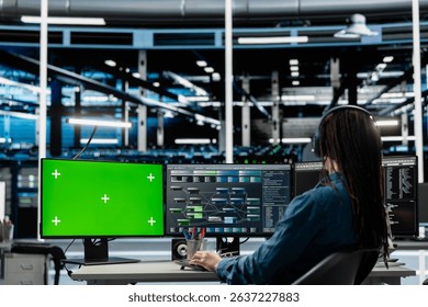 Programmer in data center using isolated screen computer to check equipment performance upgrading infrastructure. IT expert doing maintenance on supercomputers in servers room using chroma key PC