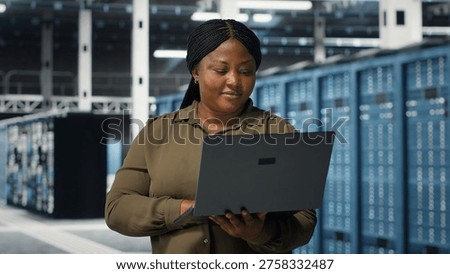 Programmer in data center using laptop to upgrade systems for increased stability. IT professional in server farm configuring infrastructure with notebook for optimum performance, camera B