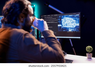 Programmer drinking coffee and doing maintenance on artificial intelligence neural networks computerized model. Tech support expert enjoying hot beverage while checking up on AI systems