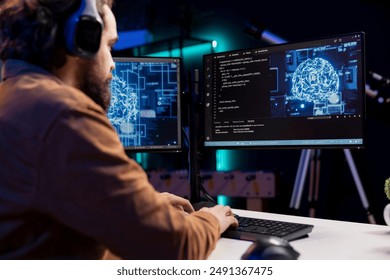 Programmer listening music while doing maintenance on artificial intelligence neural networks computerized model. Tech support expert using headphones and doing checkup on AI systems