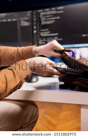 Programmer packing backpack at end of day after securing company servers from virus attacks, close up. IT remote employee finishing job shift, leaving office after building firewalls protecting data