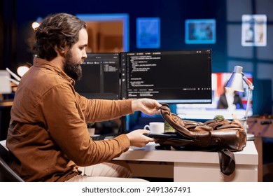 Programmer packing laptop at end of work shift after securing company servers from virus attacks. Man putting notebook in backpack, leaving office after building firewalls protecting data