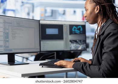 Programmer in photovoltaics facility using PC program to diagnose malfunctioning systems. African american woman coding at computer desk in solar panels manufacturing plant, reducing downtime