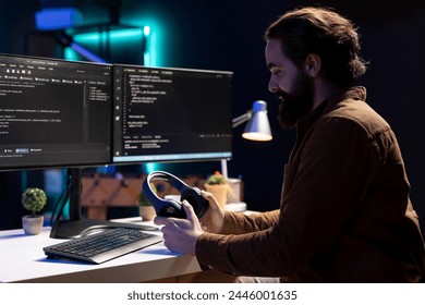 Programmer putting headphones on while implementing security measures to protect company systems and data. IT admin listening music, testing and debugging code for software applications