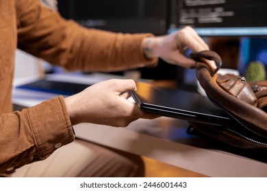Programmer putting laptop in backpack, leaving office after filtering malicious traffic from cybercriminals attempting to steal company data. Man packing notebook after finishing preventing malware