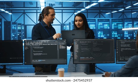 Programmer and supervisor in server room looking for equipment misconfigurations, doing brainstorming. Multiracial colleagues checking data center gear bottlenecks leading to glitches