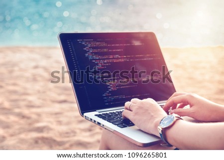 A programmer typing source codes at the beach on a sunny summer day. Studying, Working, Technology, Freelance Work Concept.