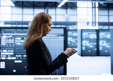 Programmer using tablet in data center with advanced tech, ensuring cybersecurity and efficient network management. IT specialist in server hub optimizing data center infrastructure with device