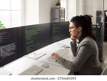 Programmer woman coding software on multiple monitors. Focused developer at computer reviews code and debugs errors with technology to improve workflow. Office focus on productivity concept. - Powered by Shutterstock - Get 15% off with code: PIKWIZARD15