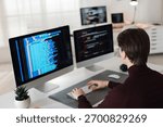 Programmer working on computer with dual monitors at white table in office