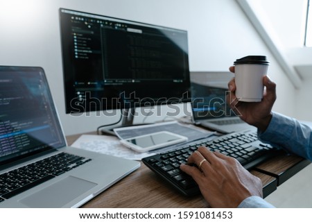 Programmer working On Computer In IT Office Typing Data Coding in software and checking code on computer screen