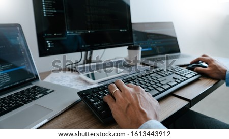 Programmer working On Computer In IT Office Typing Data Coding in software and checking code on computer screen