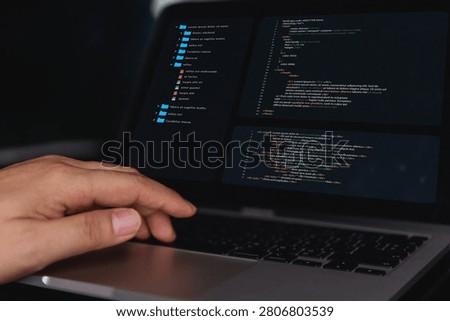 Programmer working on a dark laptop screen displaying complex website code syntax and file structures, symbolizing cyberspace technology, cyber security, and advanced IT system engineering.