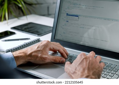 programmer writing code on laptop computer in office. website programming, software development