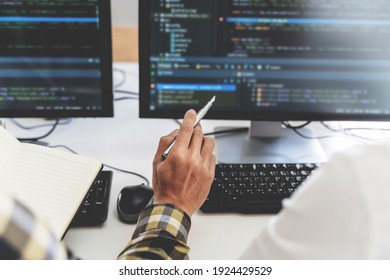 programmer writing program code with two monitors and working on new software or hacker programming developing software applications in the office. - Shutterstock ID 1924429529