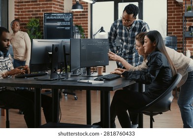 Programmers collaborating on group project compiling algorithm for new cloud computing user interface on computer screens, mixed team of software engineers brainstorming ideas looking at running code.