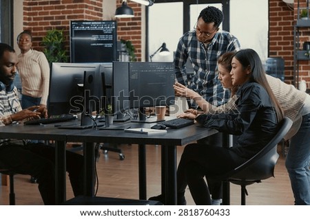 Programmers collaborating on group project compiling algorithm for new cloud computing user interface on computer screens, mixed team of software engineers brainstorming ideas looking at running code.