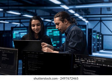 Programmers in data center using laptop to check for server performance issues, talking about solutions. Colleagues in server hub workplace fixing insufficient memory errors slowing down hardware - Powered by Shutterstock