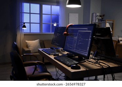Programmer's desk with computer monitors and glowing lamps in dark office at night