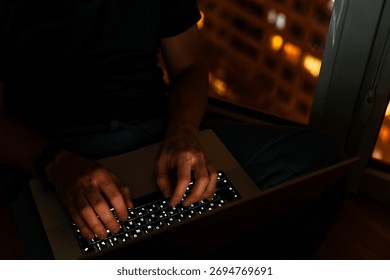 Programmer's hands are coding on a laptop in the dark with a view of the lights of the night city. The concept of a developer or hacker.
