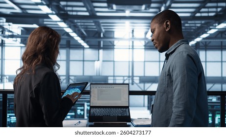 Programmers using AI technology on laptop and tablet in data center employing machine learning models. Devices used by artificial intelligence IT experts in server farm, camera B