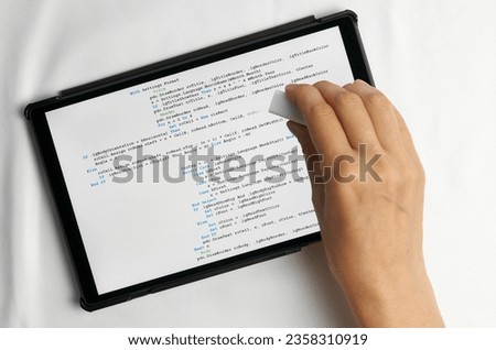 Programming and coding concept. Program code creation: hand with eraser erases erroneous part of program listing
