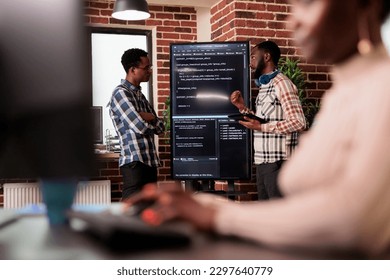 Programming engineers analyzing html code standing in front of big screen, checking errors in artificial intelligence project. Software developers working on machine learning software in it agency - Powered by Shutterstock