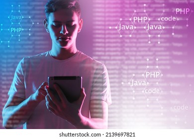 Programming languages, coding. Young programmer with a tablet against the background of programming languages. Machine code languages on a neon technological background. Programming concept. 