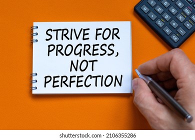 Progress or perfection symbol. Businessman writing words Strive for progress, not perfection on white note. Black calculator. Orange background. Business, progress or perfection concept. Copy space. - Shutterstock ID 2106355286
