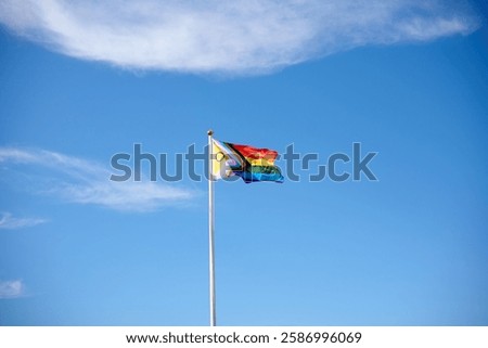 Progress pride flag waving on flagpole with blue sky background