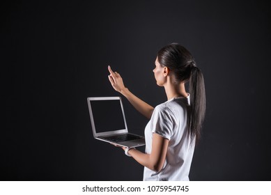 Progressive developments. Smart pleasant brunette woman holding her laptop and looking at the finger while using a sensory panel